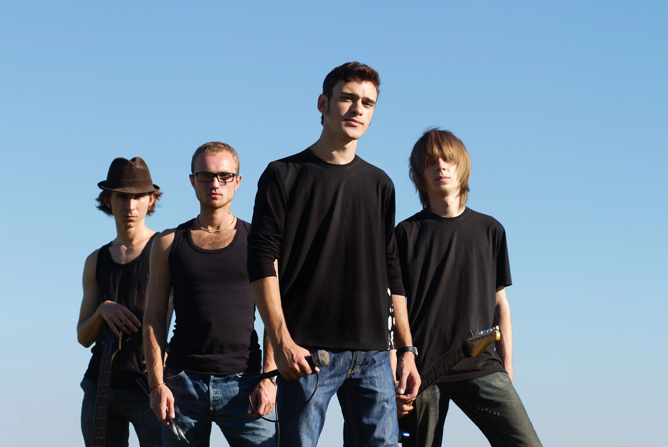 Serious young rockers posing with instruments outdoors